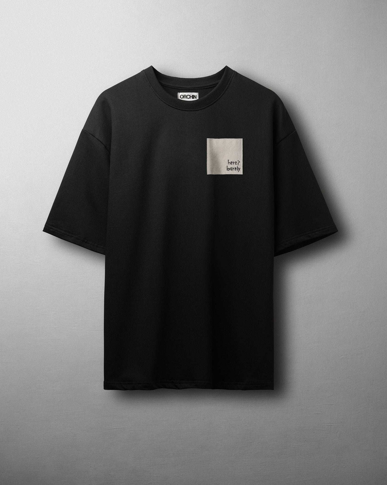 Black relaxed-fit Barely Tee with subtle embroidered patch over heart, made of 100% cotton terry, lint-free and pre-shrunk