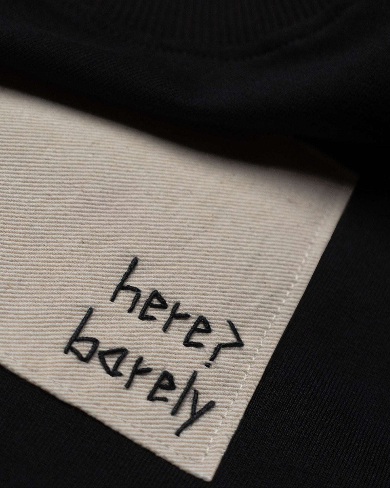 Black cotton terry The Barely Tee with hand embroidery and organic cotton twill patch.	